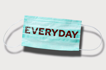 Blue disposable mask with written word: EVERYDAY. Covid routine prevention. Abstract concept of seasonal epidemic safety against virus spreading.