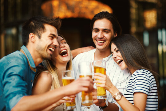 Group of young people at a summer bar toast with beer