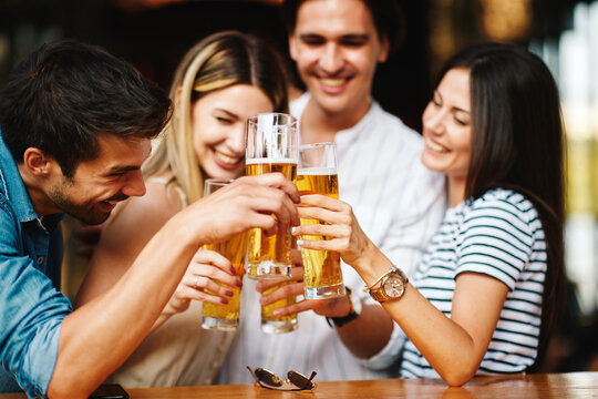 Group of young people at a summer bar toast with beer