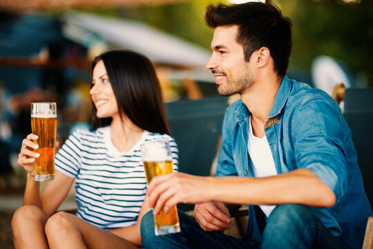 Young couple at a summer bar holding a beer in hand