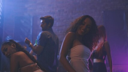 Diverse group of young people dancing at the night club, enjoying nightlife and drink