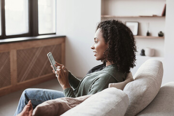 Young woman using smartphone at home. Mixed race girl looking at mobile phone. Communication,...