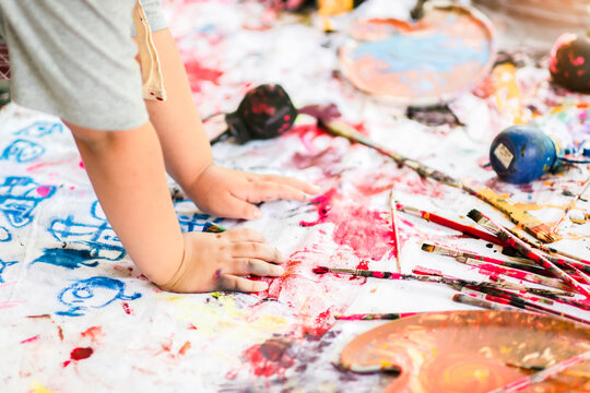 Close Up. Little Child Painting With Hands On The Canvas On The Floor At Home Using Red Paint. Finger Painting Or Art Therapy For Children. Fun Activities And Children Development For Kid Toddlers