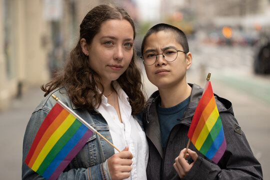 LGBTQ couple on city street serious face