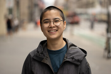 Asian non-binary person on a city street portrait smiling happy