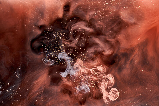 Orange smoke on black ink background, colorful fog, abstract swirling touch ocean sea, acrylic paint pigment underwater