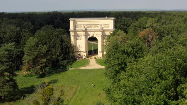 Woman running towards triumphal arch in Valtice, Moravia, drone shot.