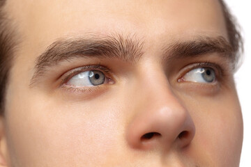 Closeup male blue eyes of young handsome man isolated on white studio background. Concept of men's health, vision, self-care, medicine and cosmetics.