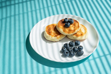 cheesecakes with sour cream and blueberries on a white plate