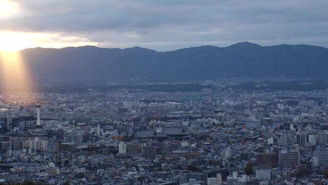 KYOTO, JAPAN - DECEMBER 2021 : Aerial high angle sunset view of Kyoto city. Scenery of mountain, streets and buildings around downtown central area. Long time lapse shot, dusk to night.