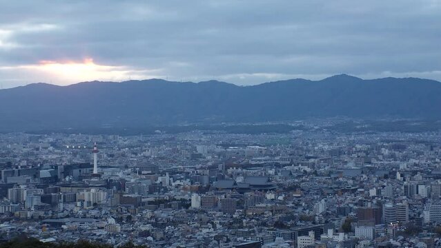 KYOTO, JAPAN - DECEMBER 2021 : Aerial high angle sunset view of Kyoto city. Scenery of mountain, streets and buildings around downtown central area. Long time lapse shot, dusk to night.