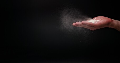 Obraz na płótnie Canvas White flour powder flying against dark background