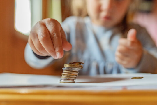 Little girl playing with coins making stacks of money. First lessons in finance. Accumulation. Credit. kid saving money for the future concept