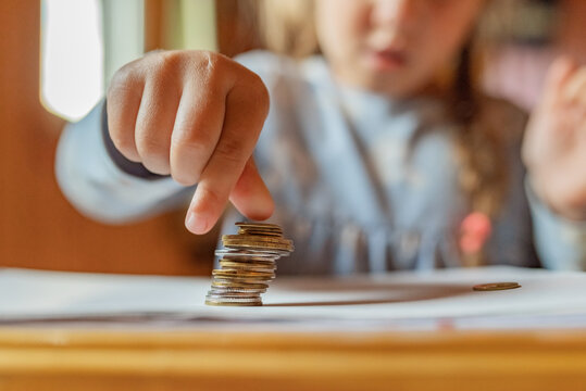 Little Girl Playing With Coins Making Stacks Of Money. First Lessons In Finance. Accumulation. Credit. Kid Saving Money For The Future Concept