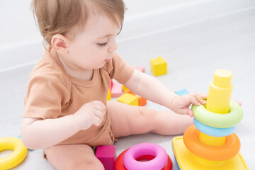 cute baby girl playing with pyramid and wooden toys at home. early children development