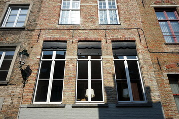 Filigrane hohe weiße Sprossenfenster im Sonnenscheinen einer restaurierten alten Backsteinfassade...