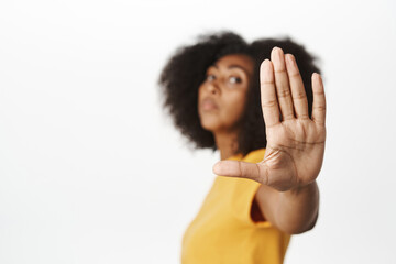 Image of african american serious-looking woman extending hand, stop, block prohibit gesture,...