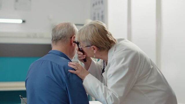 Otolaryngology specialist using otoscope to examine ear infection, helping patient with disease. Otology instrument to do ent consultation for audiology diagnosis in medical office.