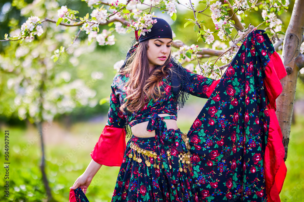 Wall mural beautiful woman in traditional gypsy dress posing in nature in spring