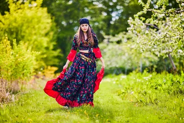Poster beautiful woman in traditional gypsy dress posing in nature in spring © czamfir