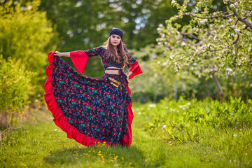 beautiful woman in traditional gypsy dress posing in nature in spring
