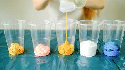 Fluid art technique. Female artist works on abstract fluid art painting, mixing acrylic colors. Painter in process create artwork in an art studio. High quality photo.