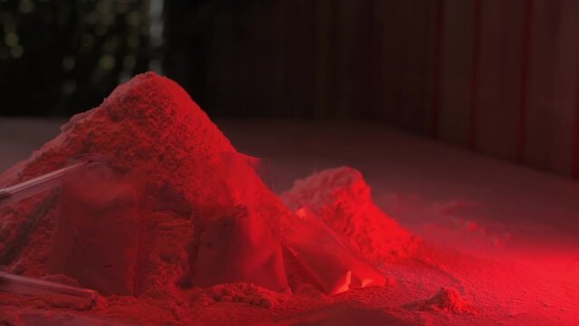 Drugs, drug dealer's house. Cocaine packaged in sachets, scales: tablets and syringes in neon light. Illegal, entry. Syringes and hard drugs.