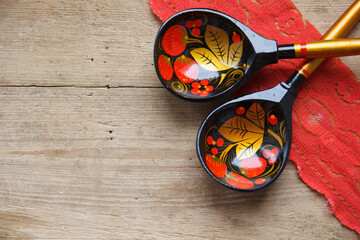Russian folk background with Khokhloma painting spoons on red lace and wooden table, place for text