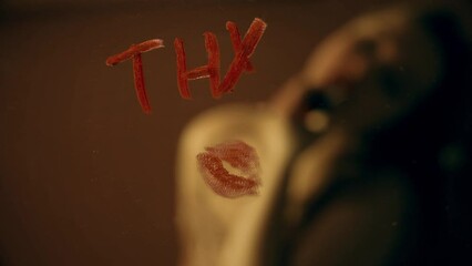The girl writes a note on the mirror with red lipstick, thx kiss Thank you