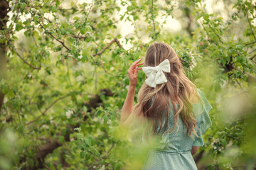white hairpin bow on women's hair. back view in blooming garden