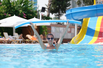 Woman is relaxing in pool and doing aqua aerobics