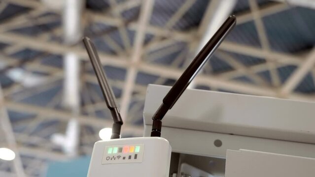A powerful wi-fi router with two antennas works in a large hall and distributes the Internet and the signal lights flash. Closeup. Shot in motion