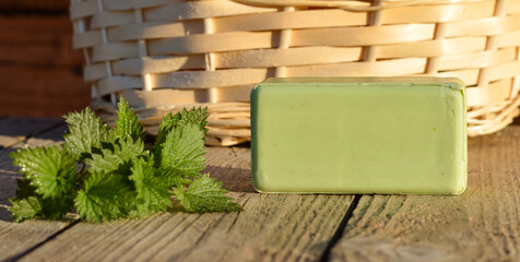 A piece of homemade green soap made with your own hands from nettles on a background of wooden boards - obrazy, fototapety, plakaty