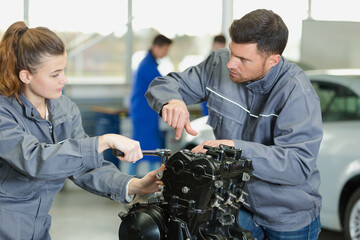 mechanic guiding apprentice working on engine