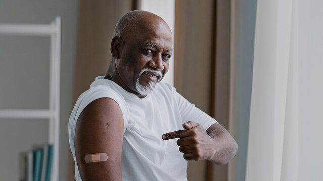 Portrait African American Old Senior Mature Man Patient Shows Medical Plaster On Shoulder Injection Mark Satisfied Male After Vaccination With Covid-19 Virus Vaccine Antivirus Dose Healthcare Concept