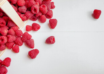 Ripe farm raspberries in a birch bark basket on a white wooden background
