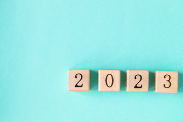2023 word is made of wooden blocks on the turquoise background. Happy New Year