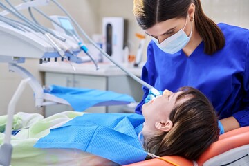Fototapeta premium Doctor dentist treats teeth to a young teenage female patient