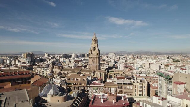 Bell tower of Murcia Cathedral with cityscape, Spain. Aerial forward. Sky for copy space