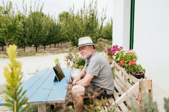 Aged farmer using tablet in garden