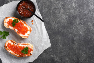 Two sandwiches with red caviar. Salmon red caviar in bowl and sandwiches server on old parchment...