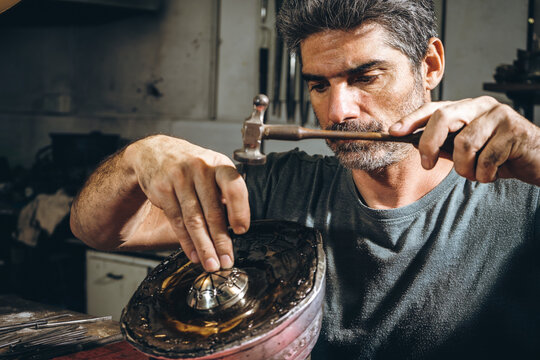 Male silversmith punching ornament on silver accessory