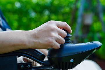 Asian elderly woman disability patient sitting on electric wheelchair in park, medical concept.