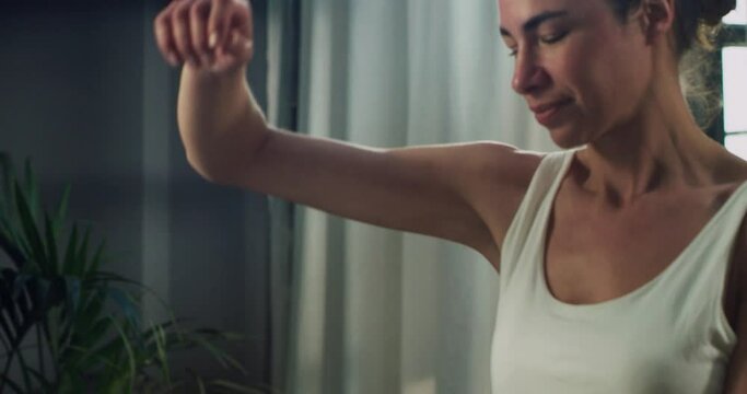 Cinematic close up of young woman applying female antiperspirant body dry spray deodorant on armpit and looking in mirror during morning beauty and personal hygiene routine at home before going out.