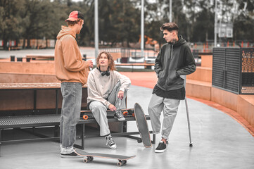 Fototapeta na wymiar Girl and two guys chatting at skatepark