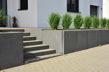 Geneigtes Wohngrundstück an Wohnhausneubau, neu terrassiert mit Natursteinmauer  oder Betonmauer...