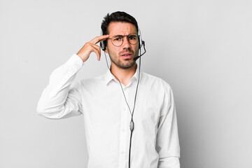 young adult hispanic man feeling confused and puzzled, showing you are insane. telemarketer concept