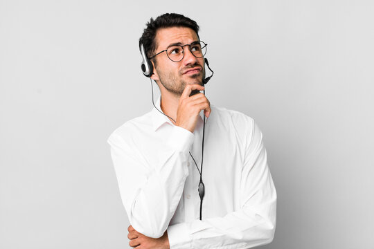 young adult hispanic man thinking, feeling doubtful and confused. telemarketer concept