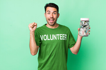 young adult hispanic man feeling shocked,laughing and celebrating success. donation concept