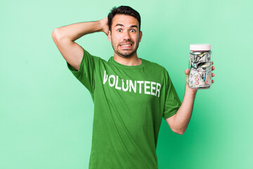 young adult hispanic man feeling stressed, anxious or scared, with hands on head. donation concept